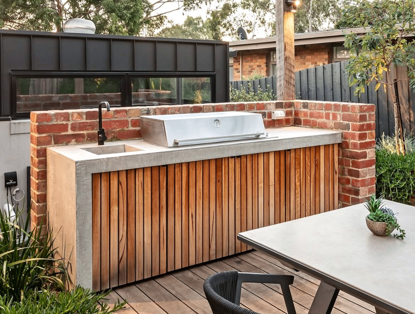 Outdoor kitchen with timber slat cabinetry, concrete benchtop and pergola by Cape Build